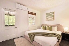 A bedroom with a bed, a nightstand, a lamp, a window with a view, and an air conditioning unit. - Harris St Apt | 5 Mins to Darling Harbour & CBD (Pyrmont)