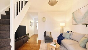 A living room with a staircase, a flat-screen TV, a sofa, a coffee table, and a lamp. - Harris St House | 5 Mins to Darling Harbour & CBD (Pyrmont)