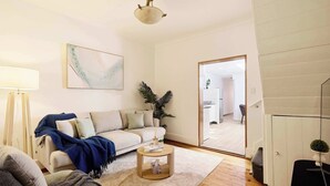 A living room with a sofa, a coffee table, a lamp, a painting, and a plant. - Harris St House | 5 Mins to Darling Harbour & CBD (Pyrmont)
