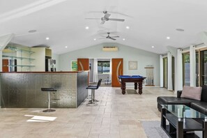 A spacious indoor area with a pool table, a bar area, and a seating area with a sofa and chairs. - Ultimate 5BR Luxury Estate Family & Group Haven (Capalaba)