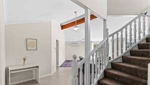 A staircase with white balusters leading to a landing, a white console table with a vase, and a framed picture on the wall.