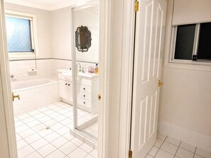 A bathroom with a bathtub, a vanity with a mirror, and a window. - Private Room in Springfield | Parking (Springfield Lakes)