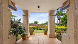 Un patio cubierto con suelo de baldosas, columnas y plantas en macetas.
