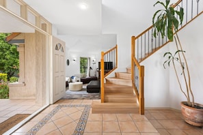 Una escalera conduce a una sala de estar con un sofá, una mesa de centro y una planta en maceta.