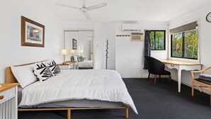 Un dormitorio con cama, escritorio, silla y ventana con vistas.