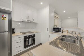 Eine moderne Küche mit weißen Schränken, einer Edelstahlspüle, einer Mikrowelle und einem Backofen.