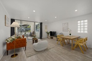 Ein modernes Wohnzimmer mit einer Couch, einem Esstisch, Stühlen, einem Fernseher und einem Balkon mit Blick.