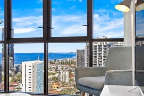 A room with a large window offering a view of the sea and cityscape. - Spacious Dual-Ensuites Apartment w/Coastaline View (Broadbeach)