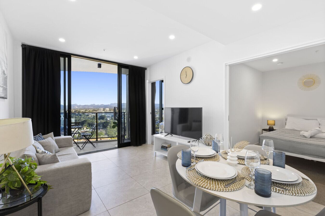 Un salon moderne comprenant un coin repas, de grandes fenêtres, un téléviseur à écran plat et un lit avec vue.