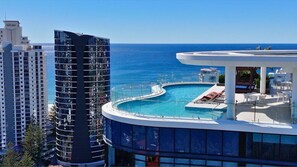 Un grattacielo con piscina sul tetto, affacciato sull'oceano.