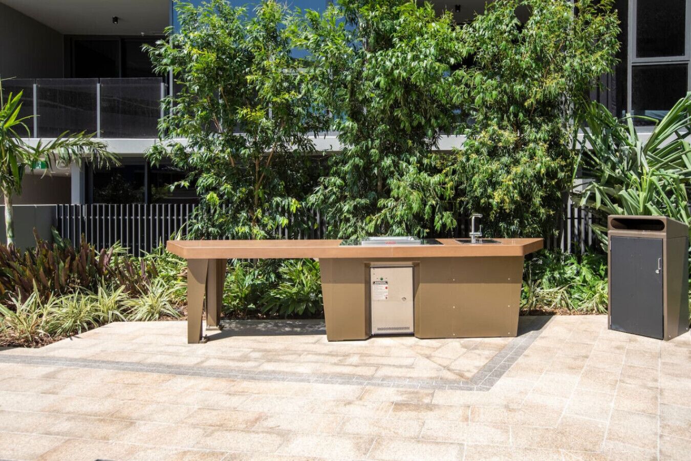 Un área de cocina al aire libre con un lavamanos empotrado y un cubo de basura.