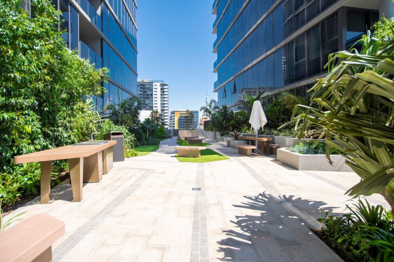 A courtyard with outdoor seating, a central planter, and surrounding greenery.