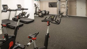 Une salle de sport équipée de vélos d’appartement, de tapis de course et d’appareils de musculation.