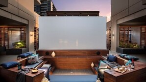 Eine Dachterrasse mit einer großen Leinwand, Holzmöbeln und stimmungsvoller Beleuchtung.