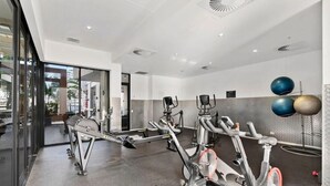 Ein modernes Fitnessstudio mit Ergometer, einer Spiegelwand und Blick ins Freie.