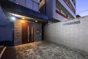 Een gebouwtoegang met een gevel van natuursteen, een houten deur en een bord waarop 'Wilshire Ave' staat.
