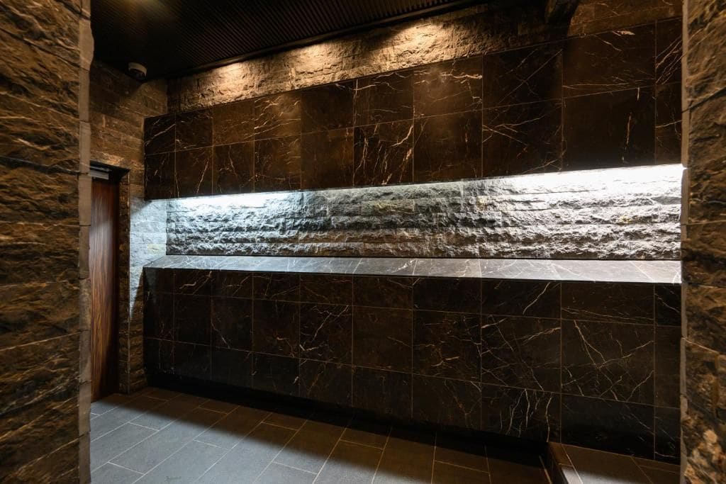 A hallway with a stone wall and a marble wall with a light strip.