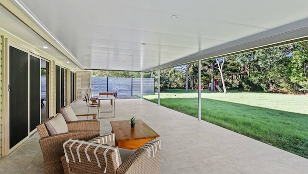 An outdoor covered patio with wicker furniture, a coffee table, and a view of a grassy yard. - Cozy & Spacious 2-Bedroom Retreat (Capalaba)