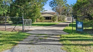 A gated entrance with a gravel path leading to a building with a metal roof. - Cozy & Spacious 2-Bedroom Retreat (Capalaba)