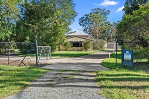 A gated entrance with a gravel path leading to a building with a metal roof. - Cozy & Spacious 2-Bedroom Retreat (Capalaba)