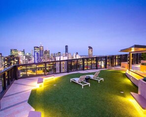A rooftop terrace with a city skyline view, outdoor seating, and a well-lit area. - Central South Brisbane 1BR w Balcony, Gym & Sauna (South Brisbane)
