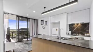 Una cocina moderna con una isla grande, horno empotrado y vista a la ciudad.