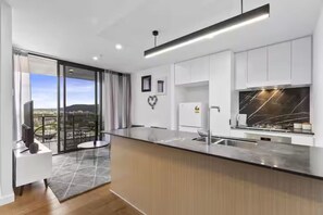 A modern kitchen with a large island, a built-in oven, and a view of the city. - Central South Brisbane 1BR w Balcony, Gym & Sauna (South Brisbane)