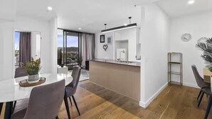 Una cocina moderna con una isla central, una zona de comedor con una mesa y sillas, y vistas al exterior a través de un ventanal.