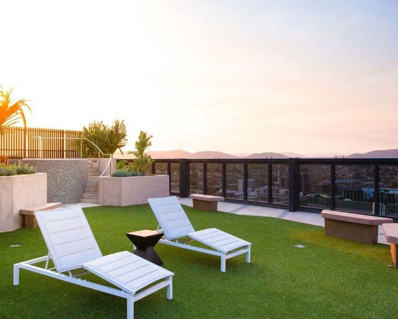 Una terraza en la azotea con dos sillones blancos, una mesita y vistas a la ciudad.