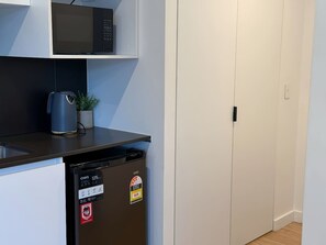 Eine kompakte Küche mit Mikrowelle, Kaffeemaschine und Geschirrspüler.