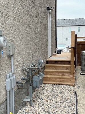 A utility area with pipes, a water meter, and a wooden deck. - Haven in the Prairies 1BR S (Winnipeg)
