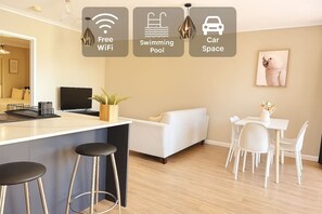 Ein moderner Wohnraum mit Küchenbereich, einem Esstisch, einer Couch und einem gerahmten Bild an der Wand.