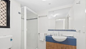 Une salle de bain équipée d’une douche, de toilettes, d’un lavabo et d’un miroir.