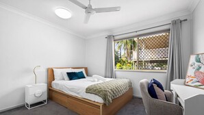 Un dormitorio con cama, mesita de noche, silla y ventana con vistas.