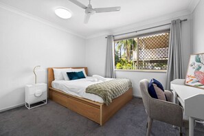Ein Schlafzimmer mit Bett, Nachttisch, Stuhl und einem Fenster mit Blick.