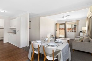 Una sala moderna con comedor, un sofá y una cocina a la vista en el fondo.