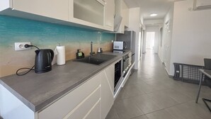 Eine moderne Küche mit grauer Arbeitsplatte, einem Spülbecken, einem Wasserkocher und einer Mikrowelle.