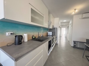 Eine moderne Küche mit grauer Arbeitsplatte, einem Spülbecken, einem Wasserkocher und einer Mikrowelle.