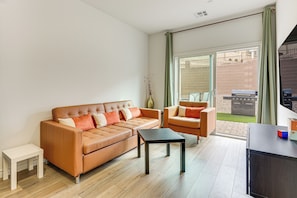 Una sala de estar con sofá, sillón, mesa de centro y mueble para televisión.