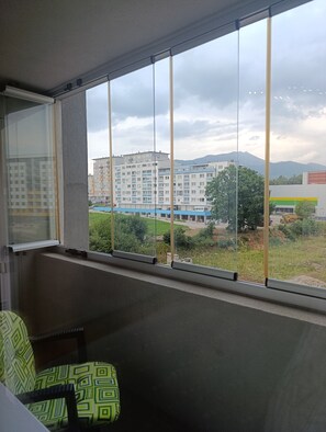 Ein Zimmer mit großem Fenster und Blick auf eine Wohngegend sowie einen Berg.