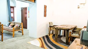 A living room with a sofa, a dining table, and a TV.