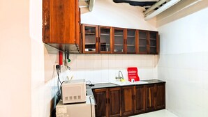 A compact kitchen with wooden cabinets, a white countertop, and a built-in microwave.