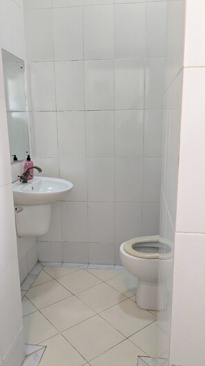 A bathroom with a white sink, a toilet, and a mirror. - The Hub Train House Hakuna Matata (Zanzibar)