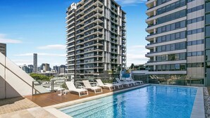 A rooftop swimming pool with lounge chairs, surrounded by high-rise buildings. - Milton apartment-2BR@MT 1905 (Milton)