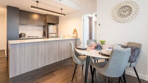 Een moderne keuken met een centraal eiland, een zithoek met stoelen en een wandklok.