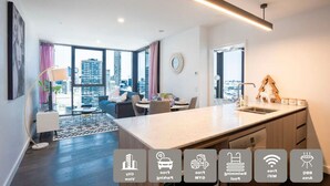 Een modern appartement met een eethoek, keuken en grote ramen met uitzicht over de stad.
