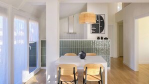 A modern dining area with a white table, two chairs, a black vase, and a woven light fixture. - Loft PENTHOUSE on the BEACH with 2 terraces (Zarautz)