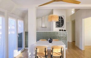A modern dining area with a white table, two chairs, a black vase, and a woven light fixture. - Loft PENTHOUSE on the BEACH with 2 terraces (Zarautz)