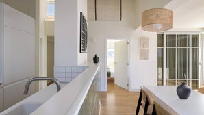 A modern kitchen with a white countertop, a hanging light fixture, and a view into the dining area. - Loft PENTHOUSE on the BEACH with 2 terraces (Zarautz)