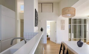 A modern kitchen with a white countertop, a hanging light fixture, and a view into the dining area. - Loft PENTHOUSE on the BEACH with 2 terraces (Zarautz)
